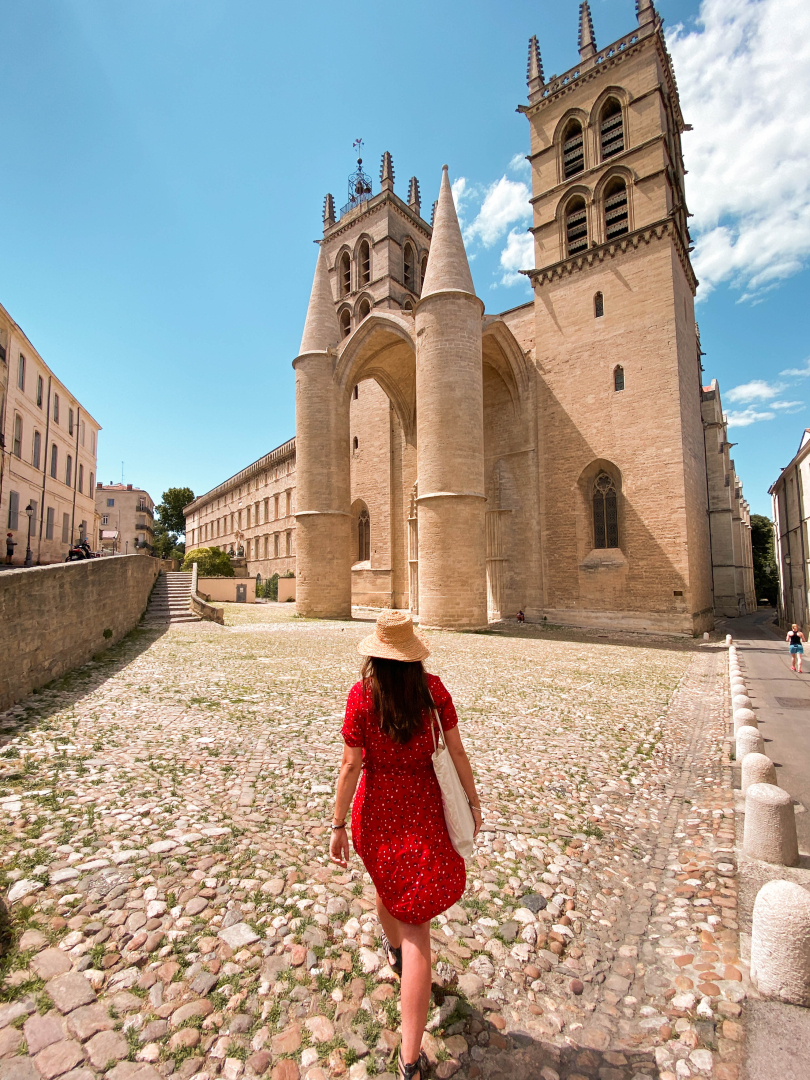 Photo d'une jeune fille en robe rouge marchant sur le parvis de la cathédrale Saint-Pierre