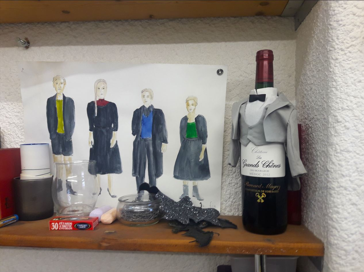 Sur une étagère de l'atelier, croquis de costume et une bouteille de vin habillée par la costumière Kristine Pasternaka