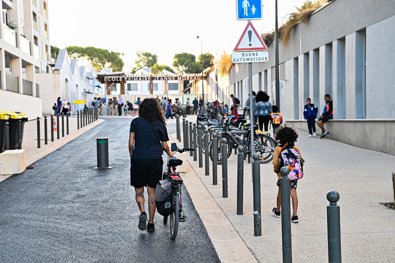 Rue piétonne devant l'école Jeanne Moreau avec femme, enfant et vélo