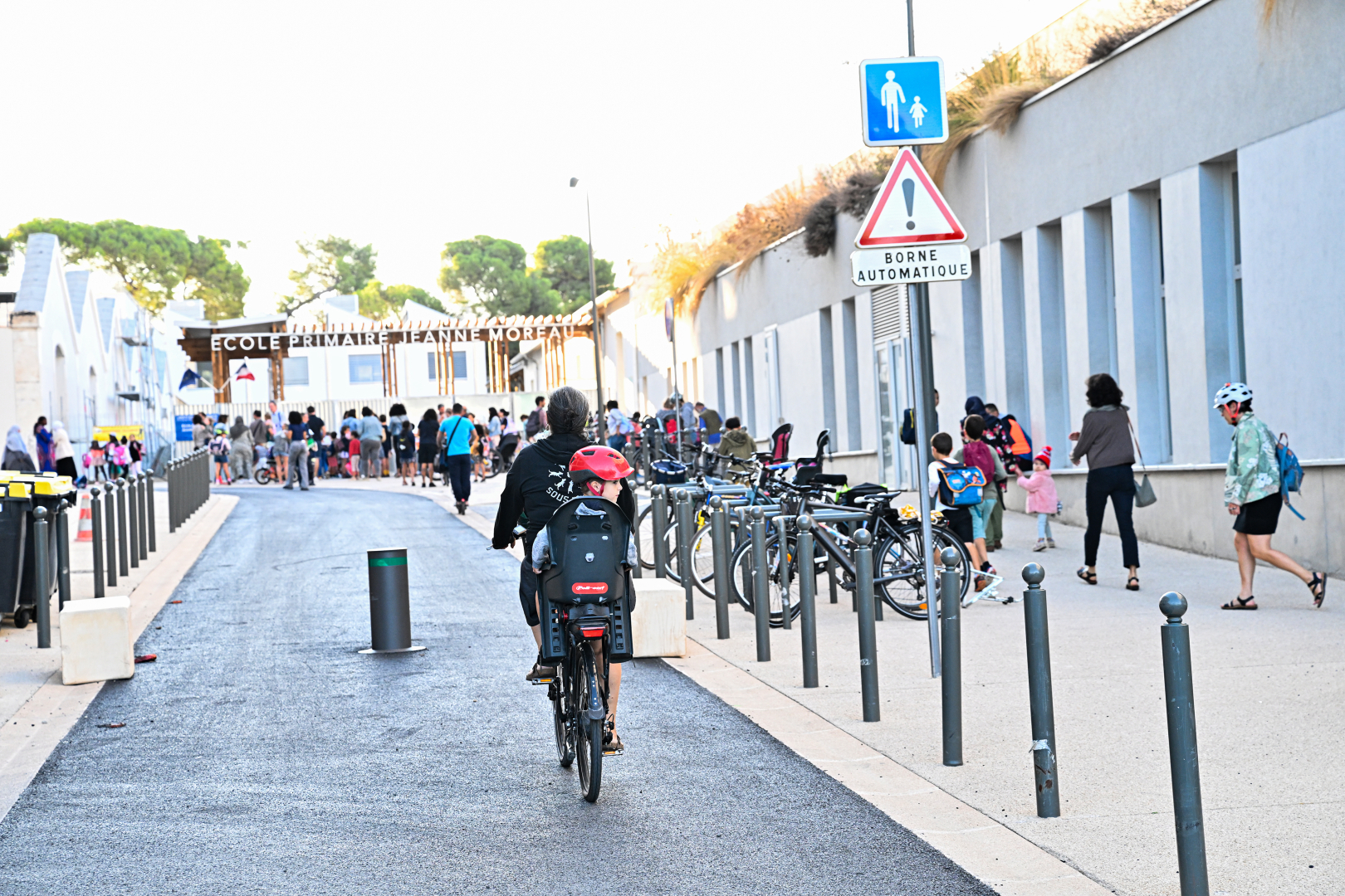 Rue piétonne école Jeanne Moreau, parvis réaménagé et sécurisé, femme et enfant à vélo 