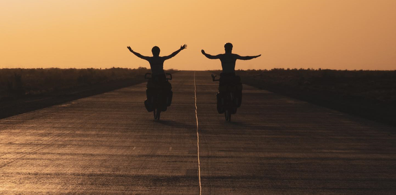 Affiche du film Sunriders, deux jeunes étudiants à vélo partent à l'aventure sur fond de soleil couchant