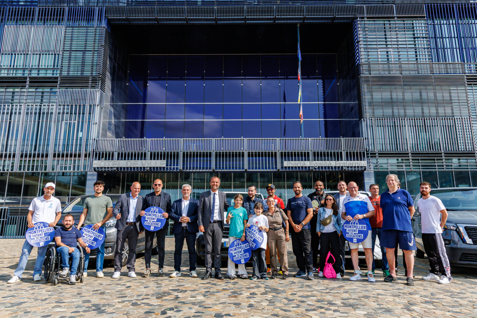 photo de groupe élus et associations sportives devant l'hôtel de ville véhicules 