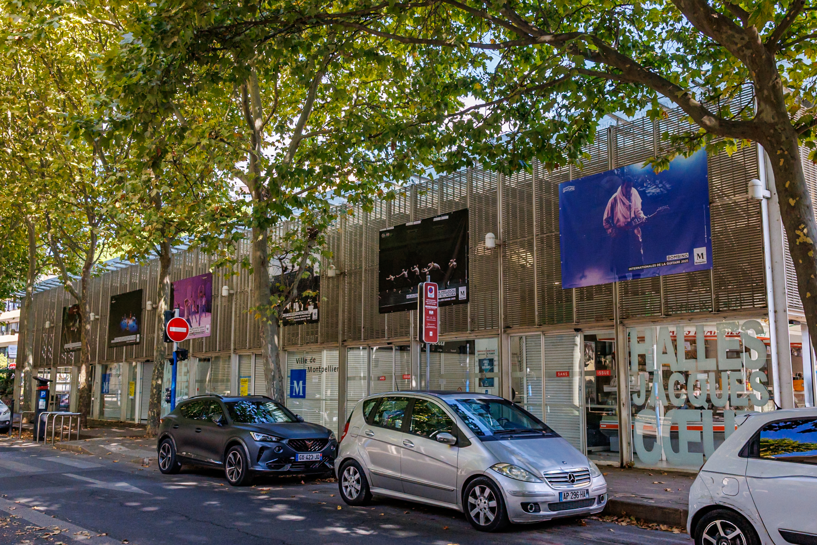 halles Jacques Coeur avec affiches des festivals arbres voitures en stationnement