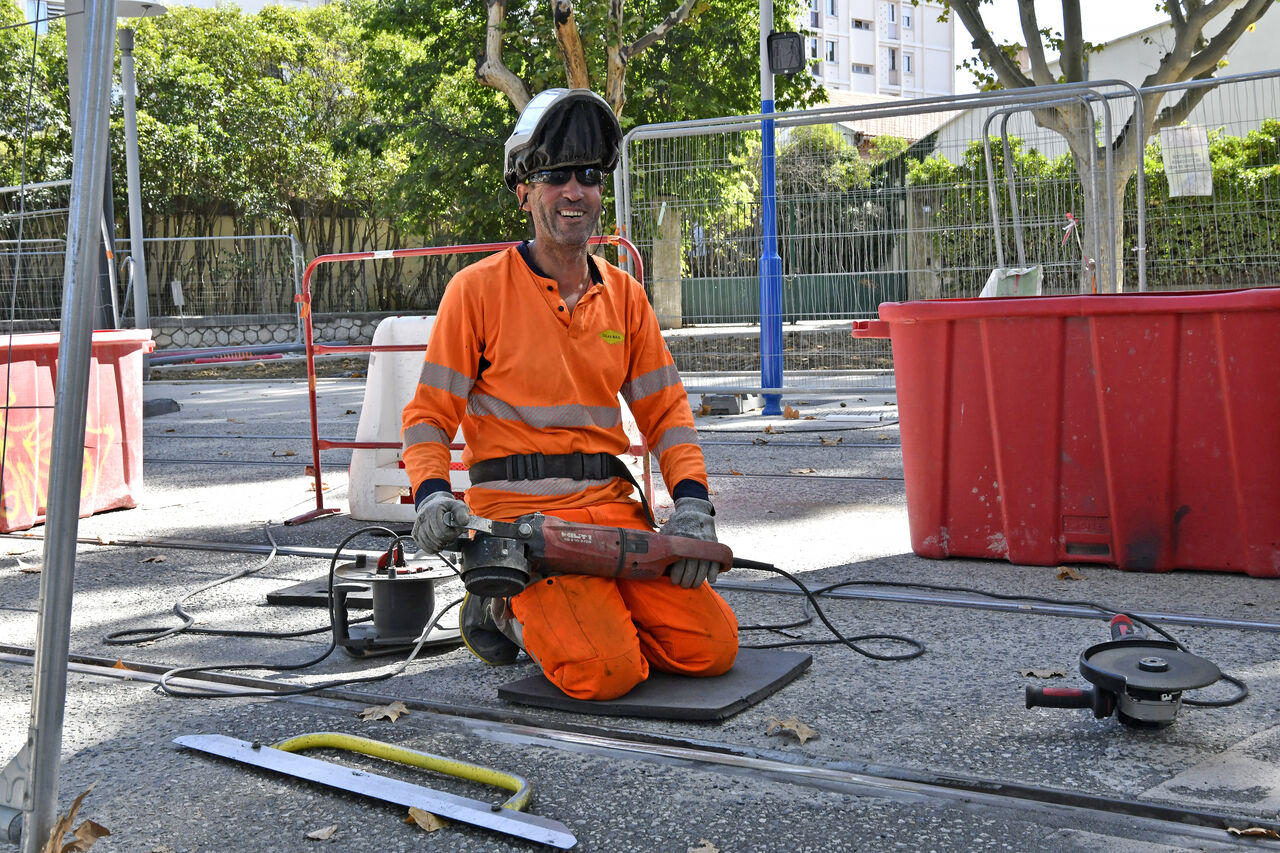 Lakhdar, soudeur sur le chantier de la ligne 5, avec une meuleuse. Rails, barrières de protection, végétation...