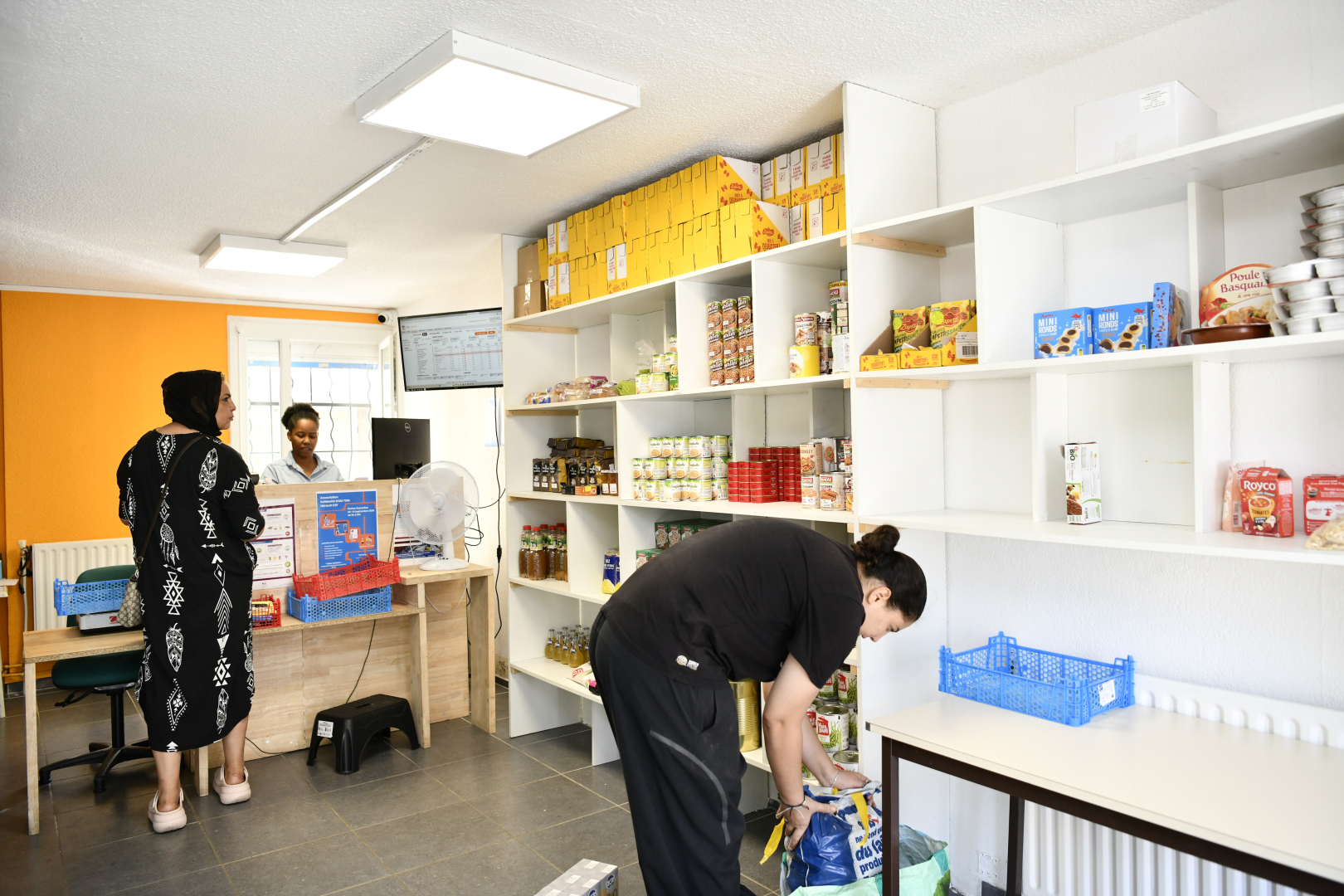produits dans les rayons de l'épicerie solidaire, clientes, caissière