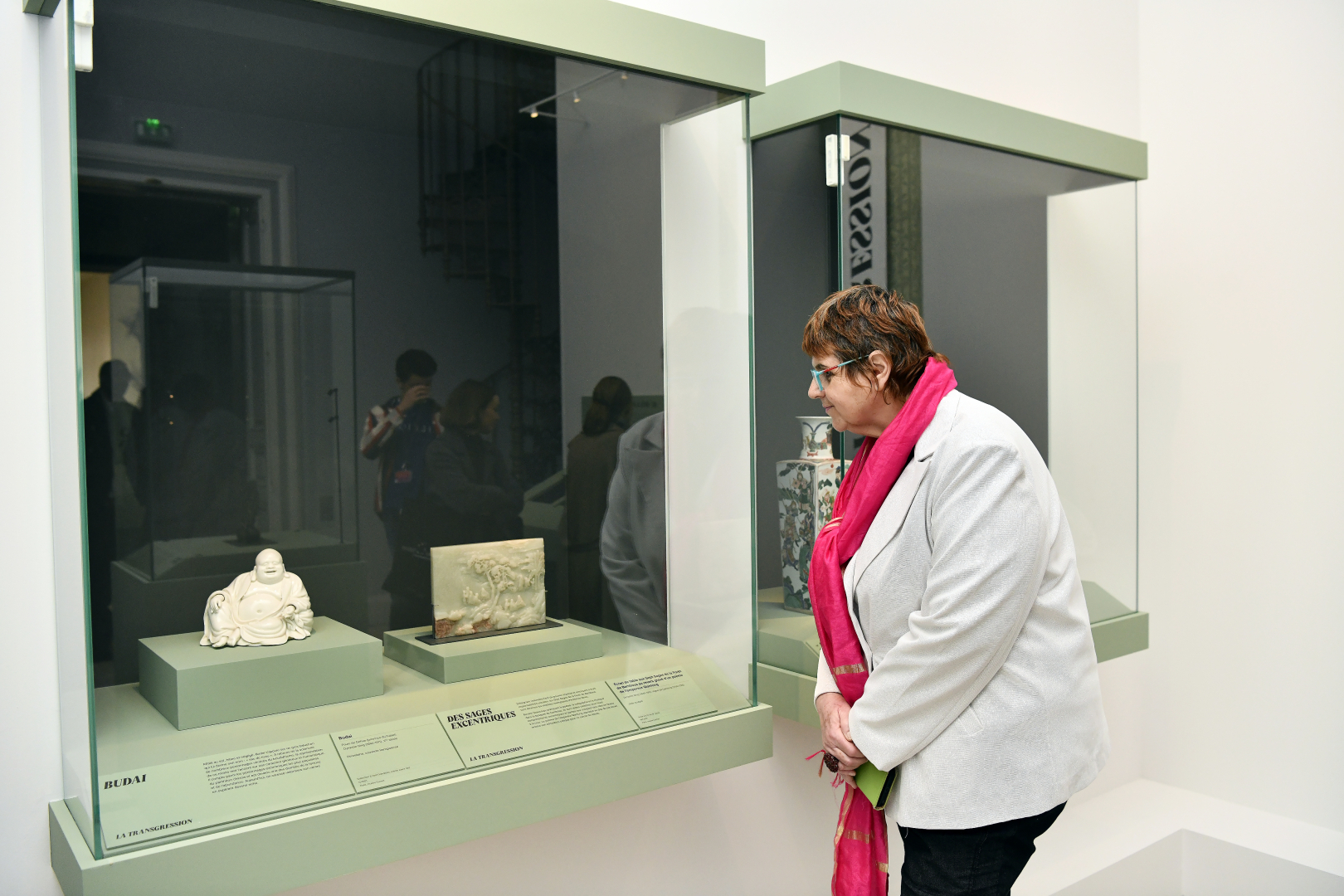 présidente du musée Guimet devant une vitrine présentant des sculptures 
