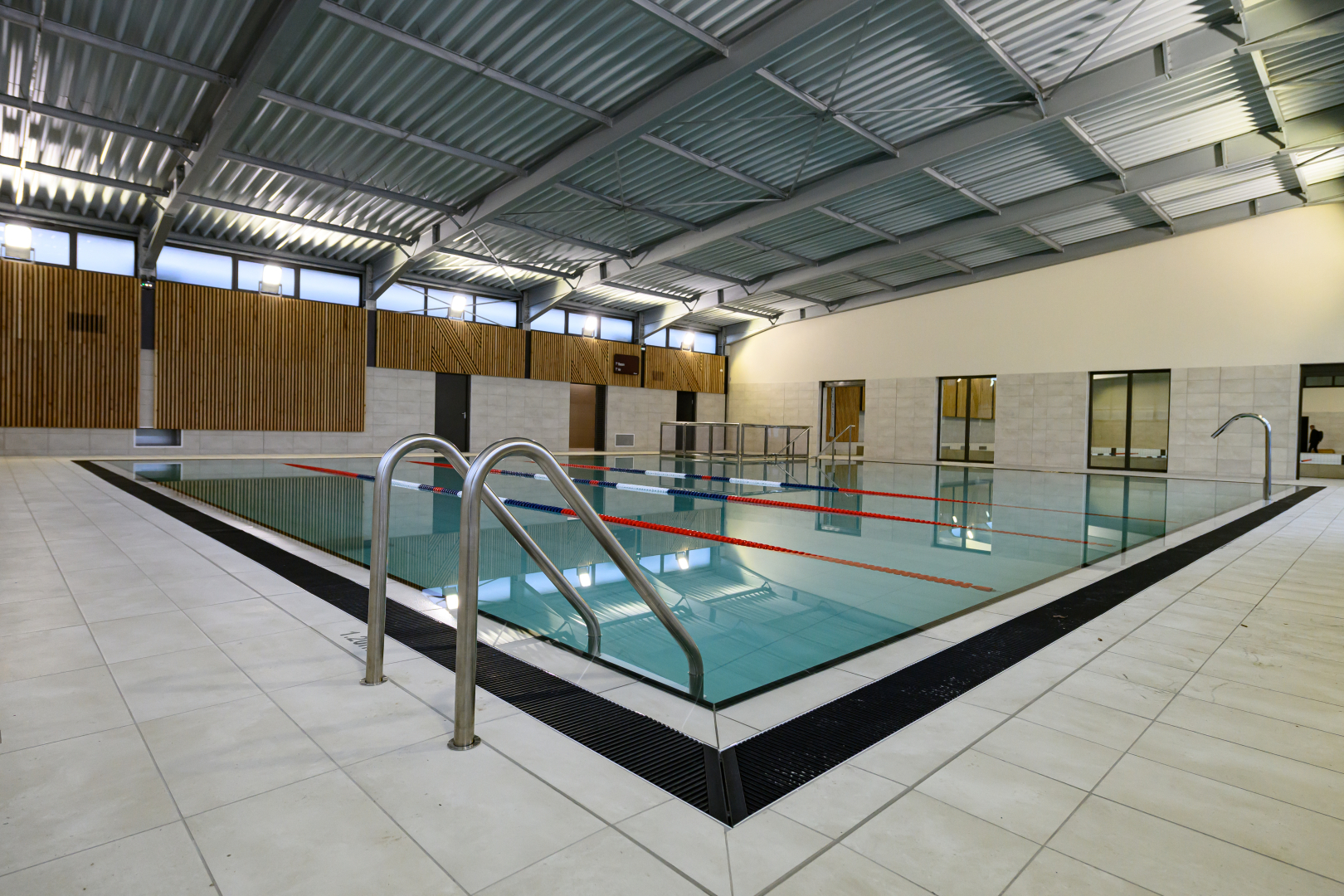 nouveau bassin intérieur de 15 mètres sur 15 avec jet d'eau escalier murs toit