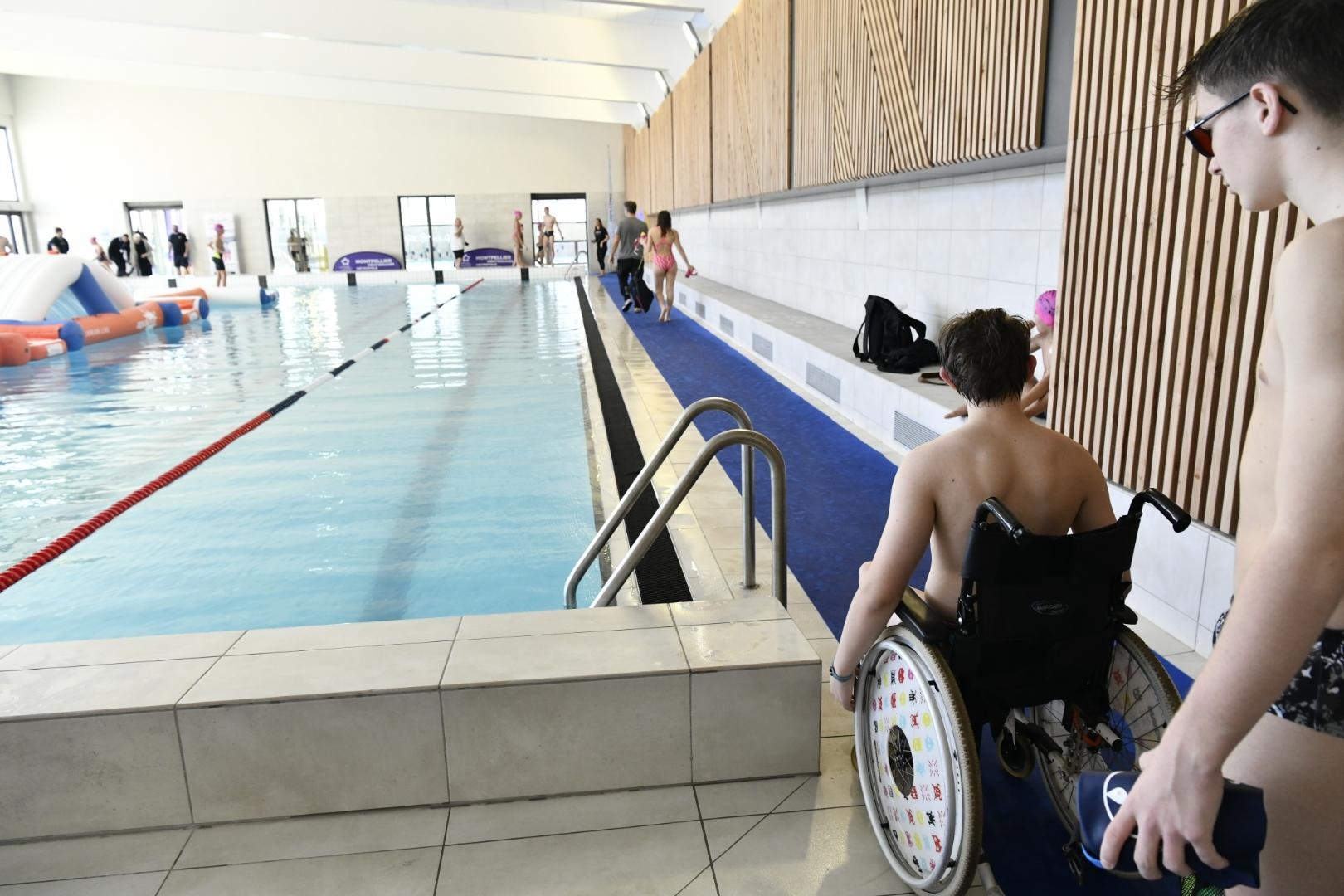 bassin intérieur personne en fauteuil accompagnant maître nageur