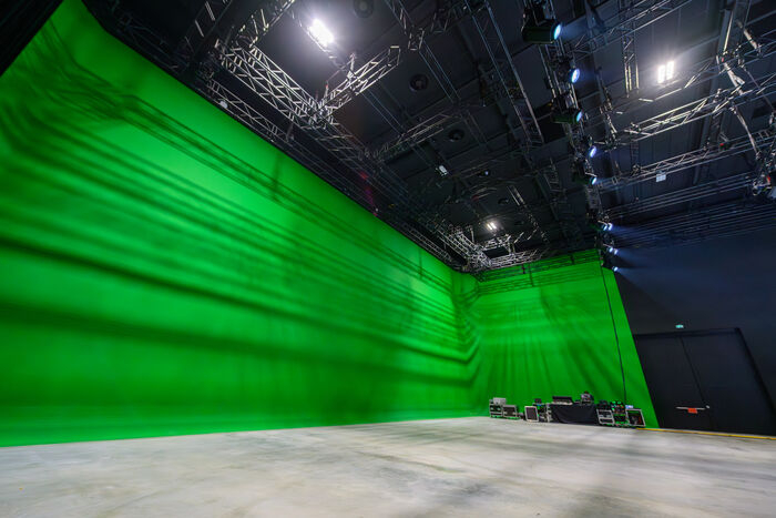 espace de tournage nu avec grand fond vert, sol gris, éclairage 