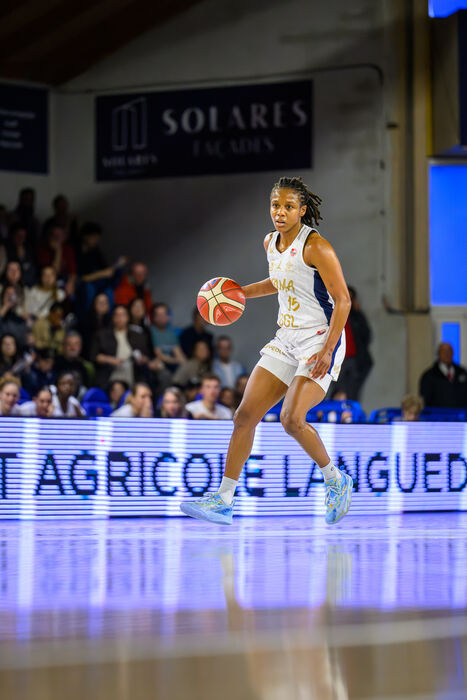 Joueuse Kyra Lambert en action sur le parquet, public en arrière-plan 