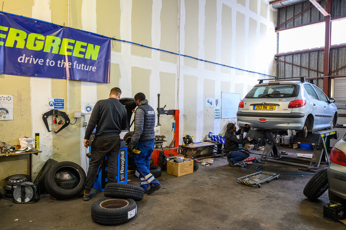 voiture sur&eacute;lev&eacute;e, outils, ouvriers, pneus dans le garage solidaire