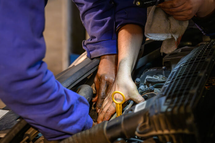 mains dans le cambouis d'un moteur de voiture