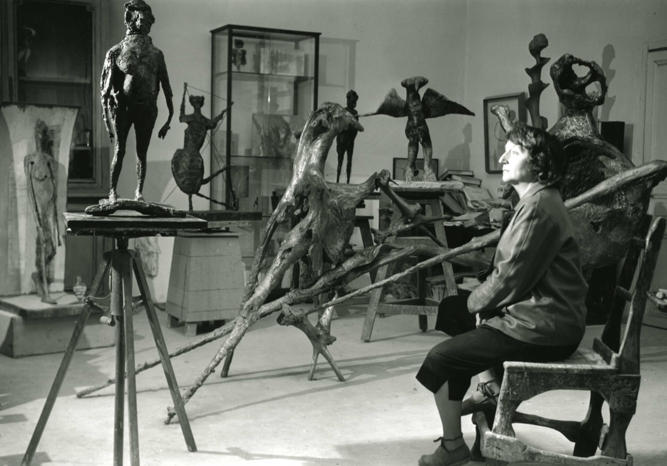 Germaine Richier, assise au milieu de ses oeuvres dans son atelier à Paris, en 1956