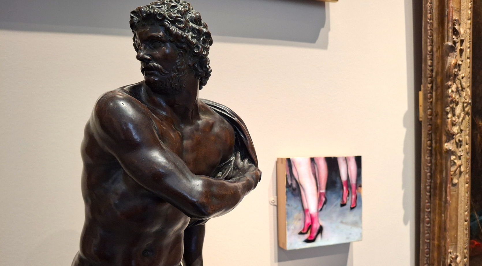 Buste de bronze d'un  personnage de mythologie semblant tourner la tête devant un petit tableau de femmes en talons rouges