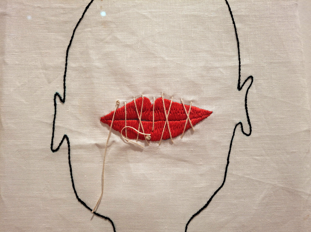 Un visage avec une bouche rouge, cousue de fil