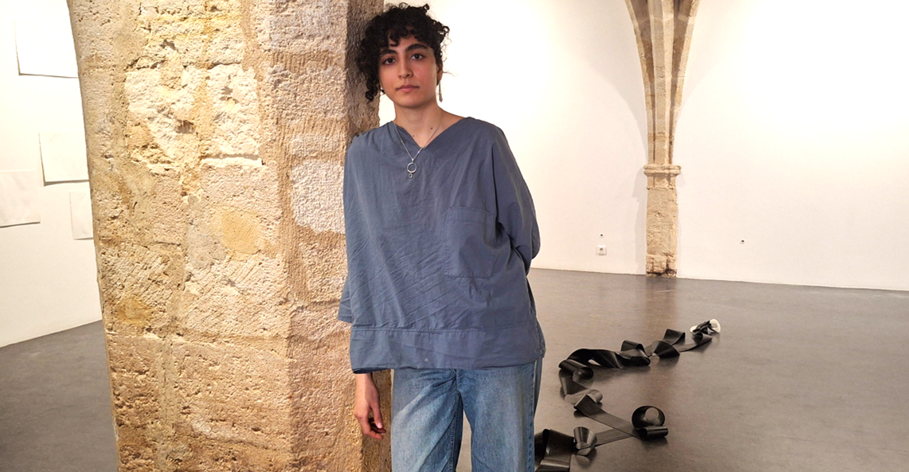 Portrait de Melika Sadeghzadeh debout contre un pilier de la galerie Saint-Ravy