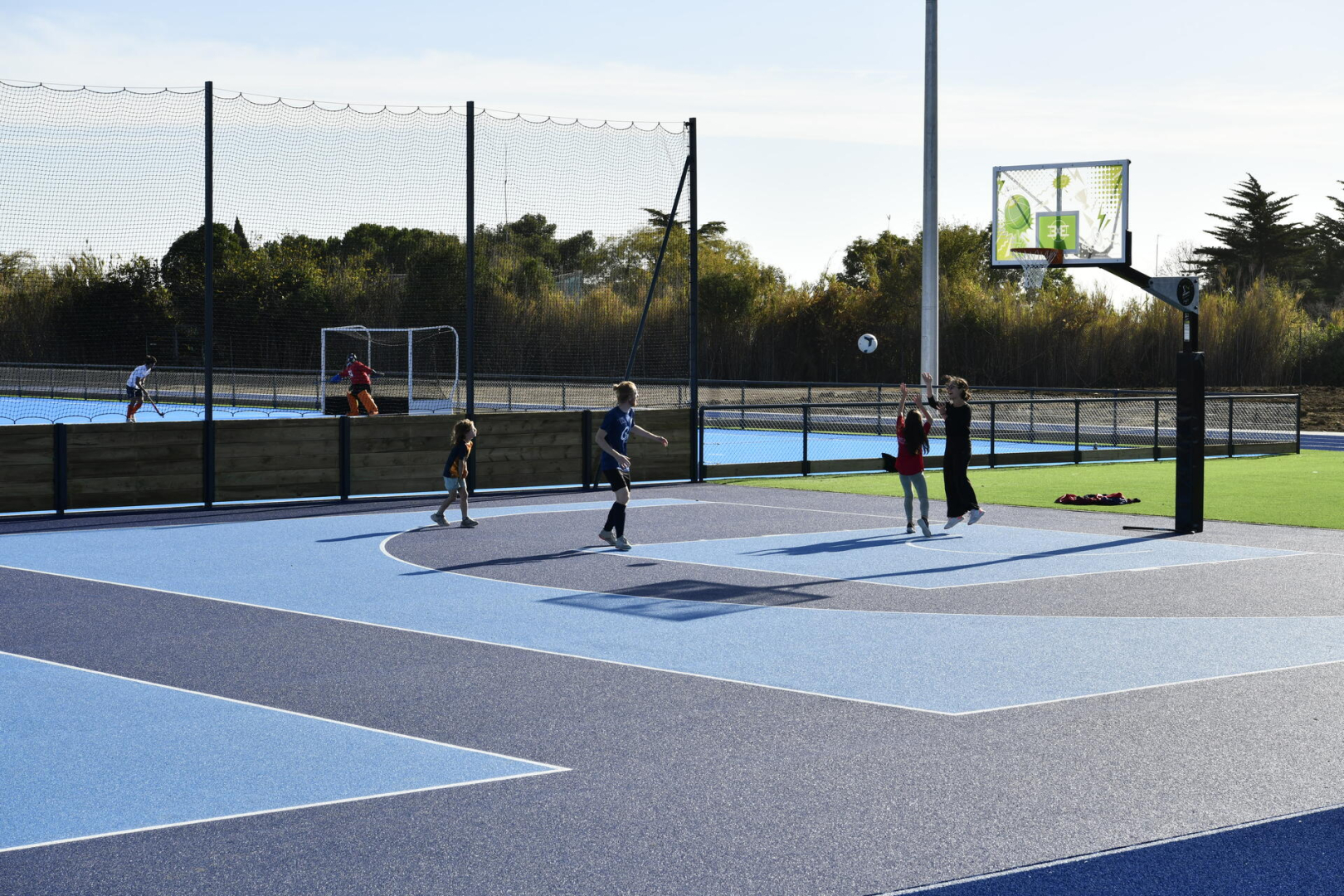 terrain de basket extérieur, piste d'athlétisme, pelouse, jeunes qui jouent
