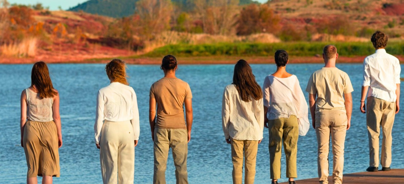 Danseurs debout, de dos, devant un lac