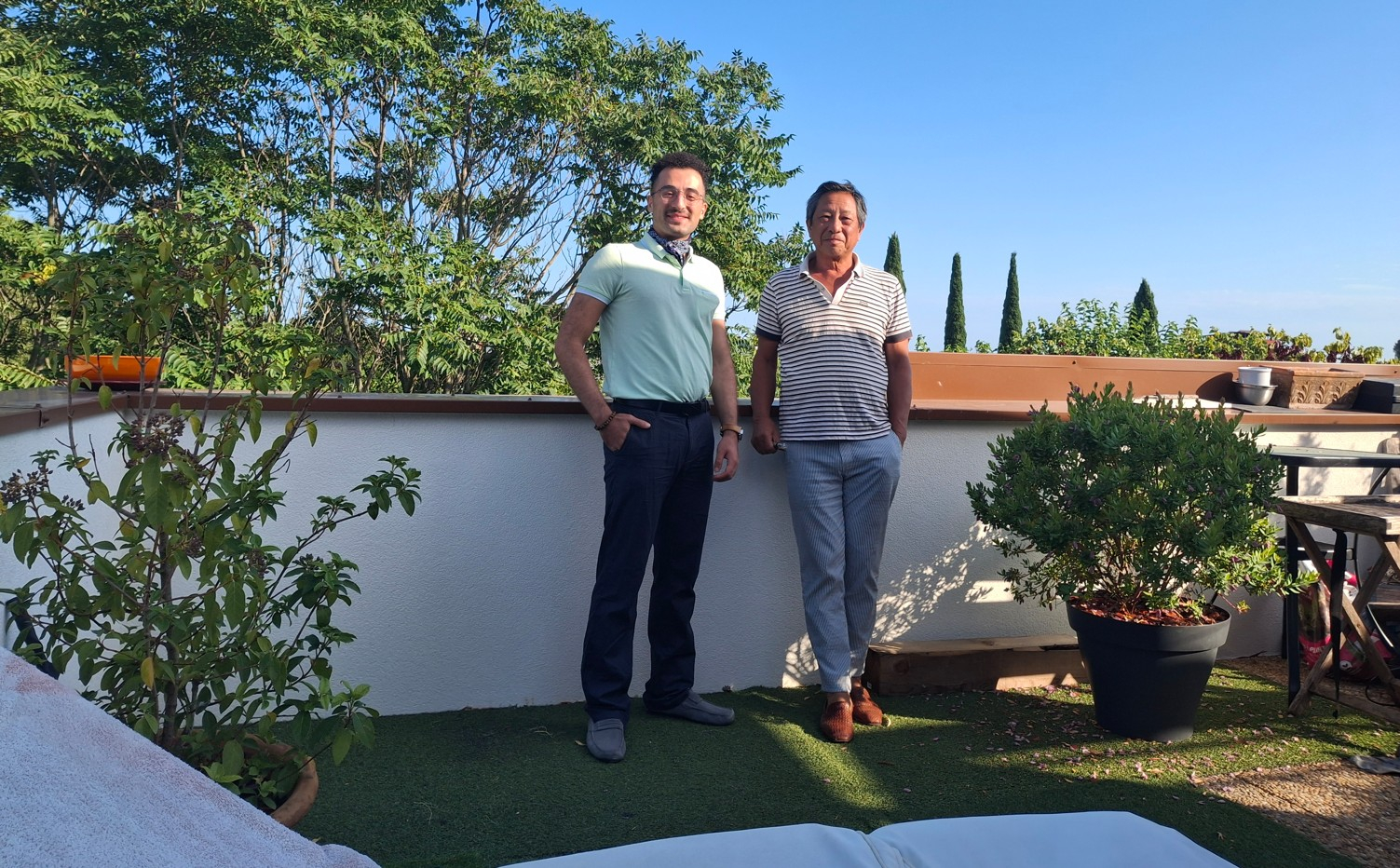 Jean et Amin sur la terrasse ouverte, avec plantes, transat et barbecue