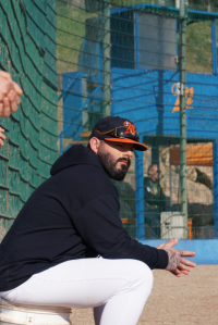 Tim Smith manager des Barracudas assis au bord du terrain, filet de protection, casquette