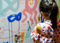 une filette qui peint sur un mur 