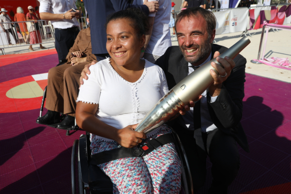 adolescente en fauteuil et torche paralympique