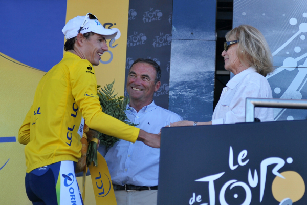 Daryl Impey avec le maillot jaune sur le podium aux côtés de Bernard Hinault