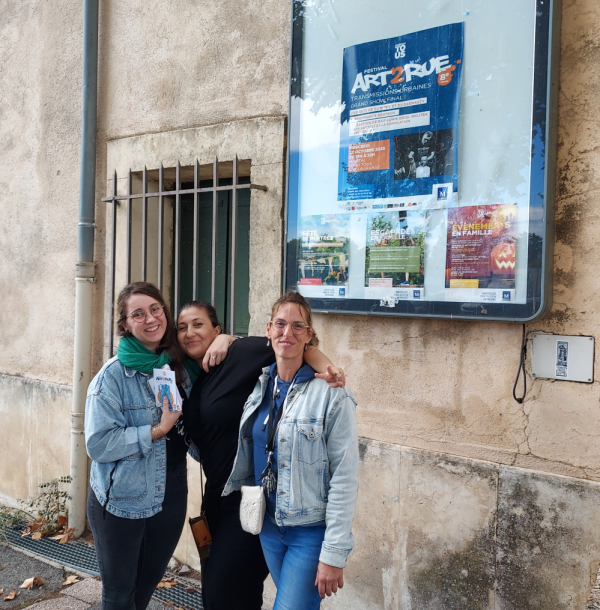 trio d'animatrices organisatrices de l'évènement devant l'espace Léo Lagrange avec affiche festival Art2Rue