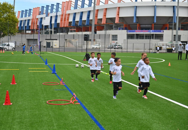 plots et cerceaux, enfants en tenue qui courent, pelouse synthétique neuve, stade la Mosson en arrière-plan