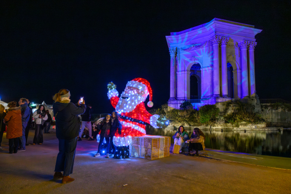 Château d'eau du Peyrou et son bassin illuminés, végétation, personnes qui se prennent en photo devant un grand Père Noël illuminé