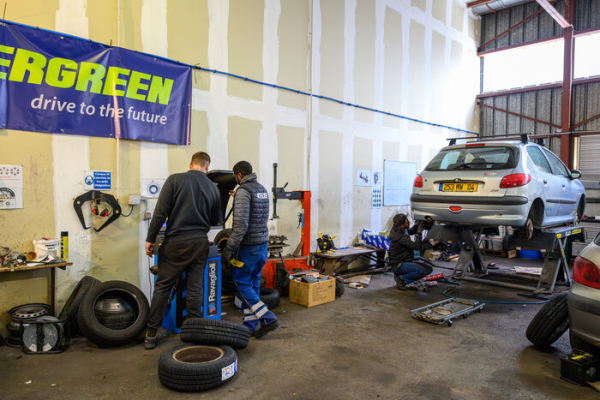 voiture sur&eacute;lev&eacute;e, outils, ouvriers, pneus dans le garage solidaire