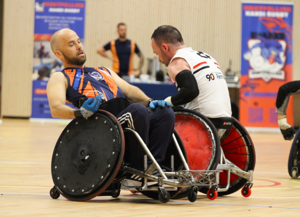 deux joueurs de rugby fauteuil en action sur le parquet