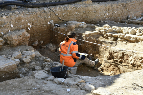 archéologue au travail, outils, strates de terrain visibles, pierres