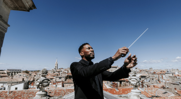 Roderick Cox, le nouveau directeur musical de l'opéra orchestre national Montpellier dirigeant au dessus des toits de la ville