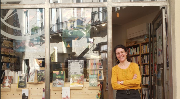 Magali, la gérante de la Librairie La Géosphère sur le pas de porte de la librairie