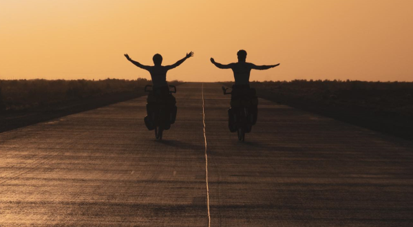 Affiche du film Sunriders, deux jeunes étudiants à vélo partent à l'aventure sur fond de soleil couchant